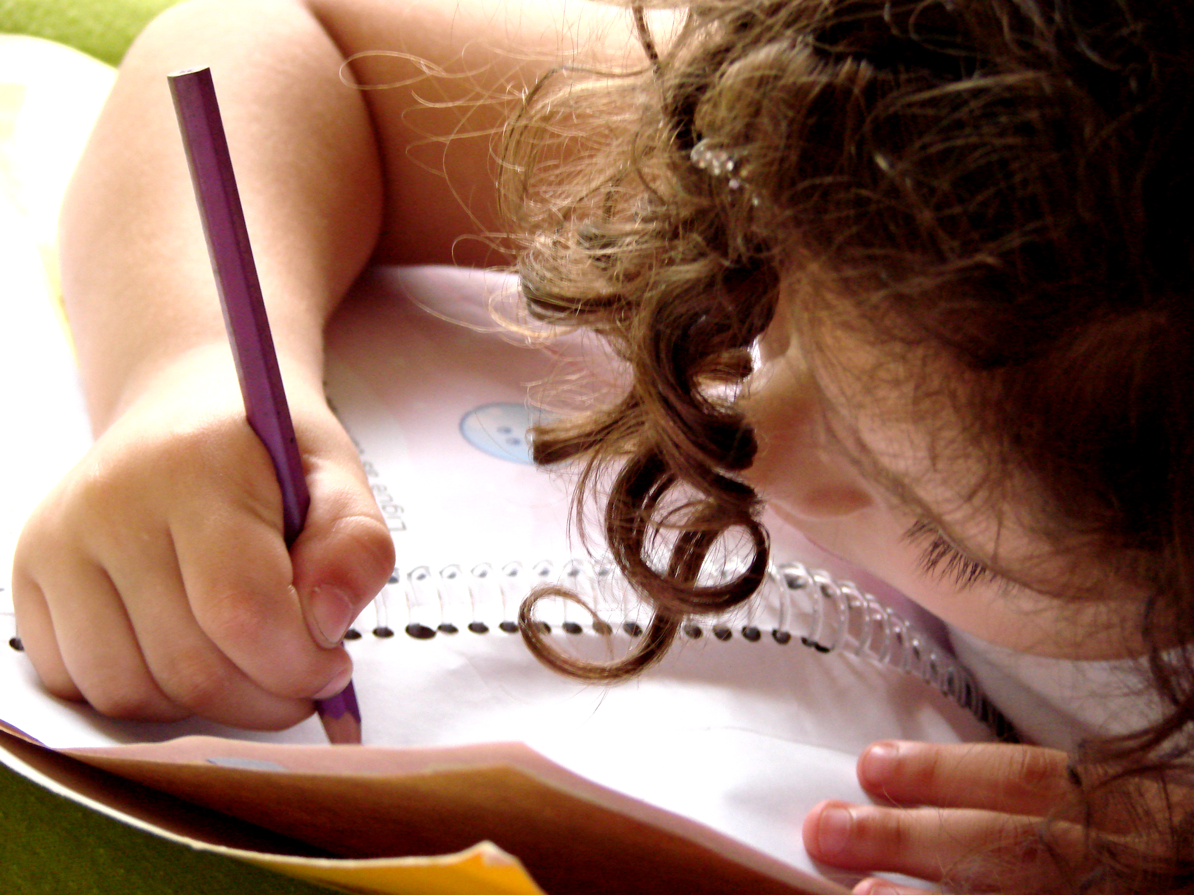 Пишем историю школы. Дети сочиняют. Девочка пишет письмо. Смешная девочка пишет. Ребенок пишет письмо.